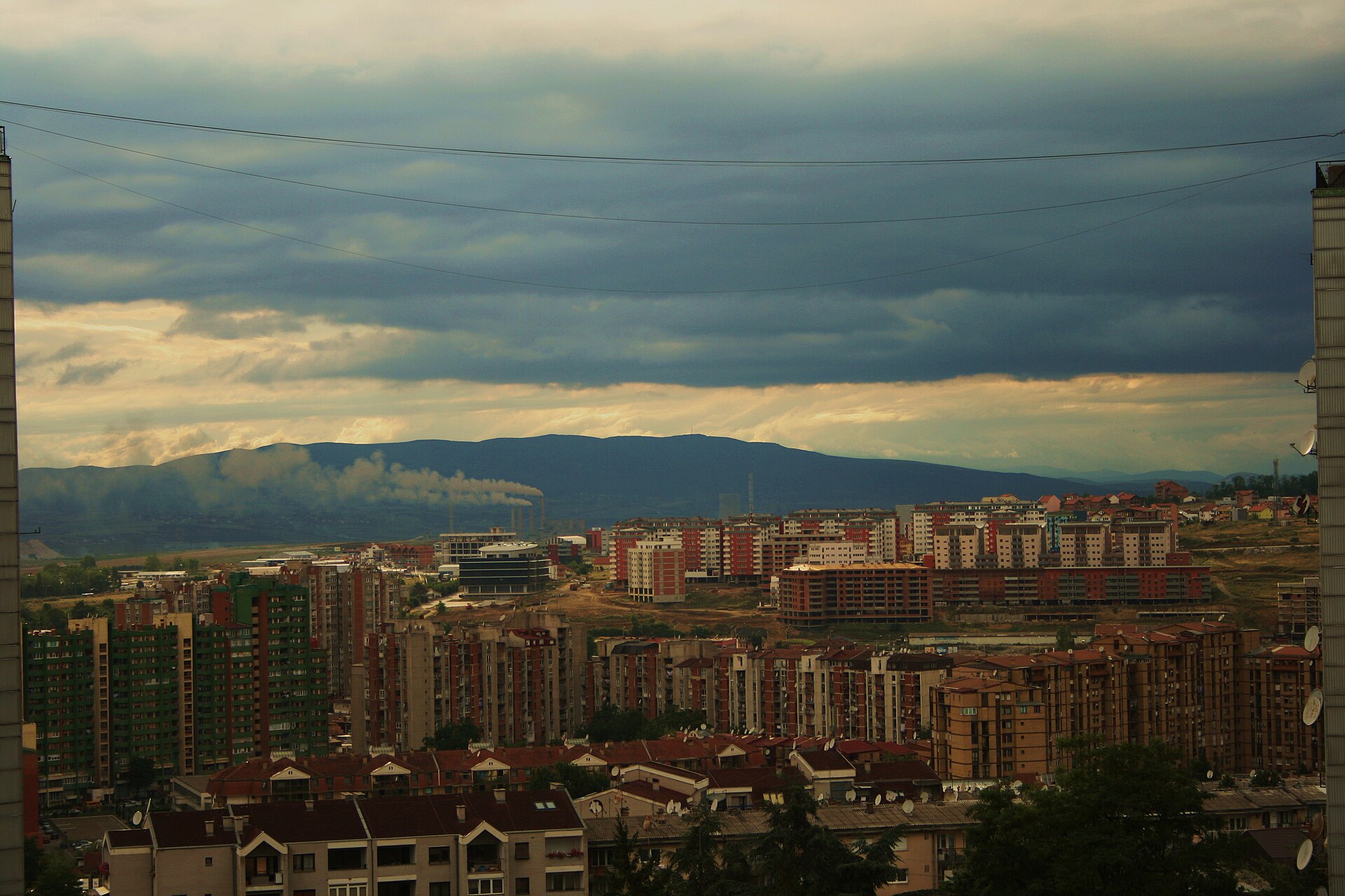 Pamje mbi çatitë e Prishtinës, Kosovë, me kodra në horizont